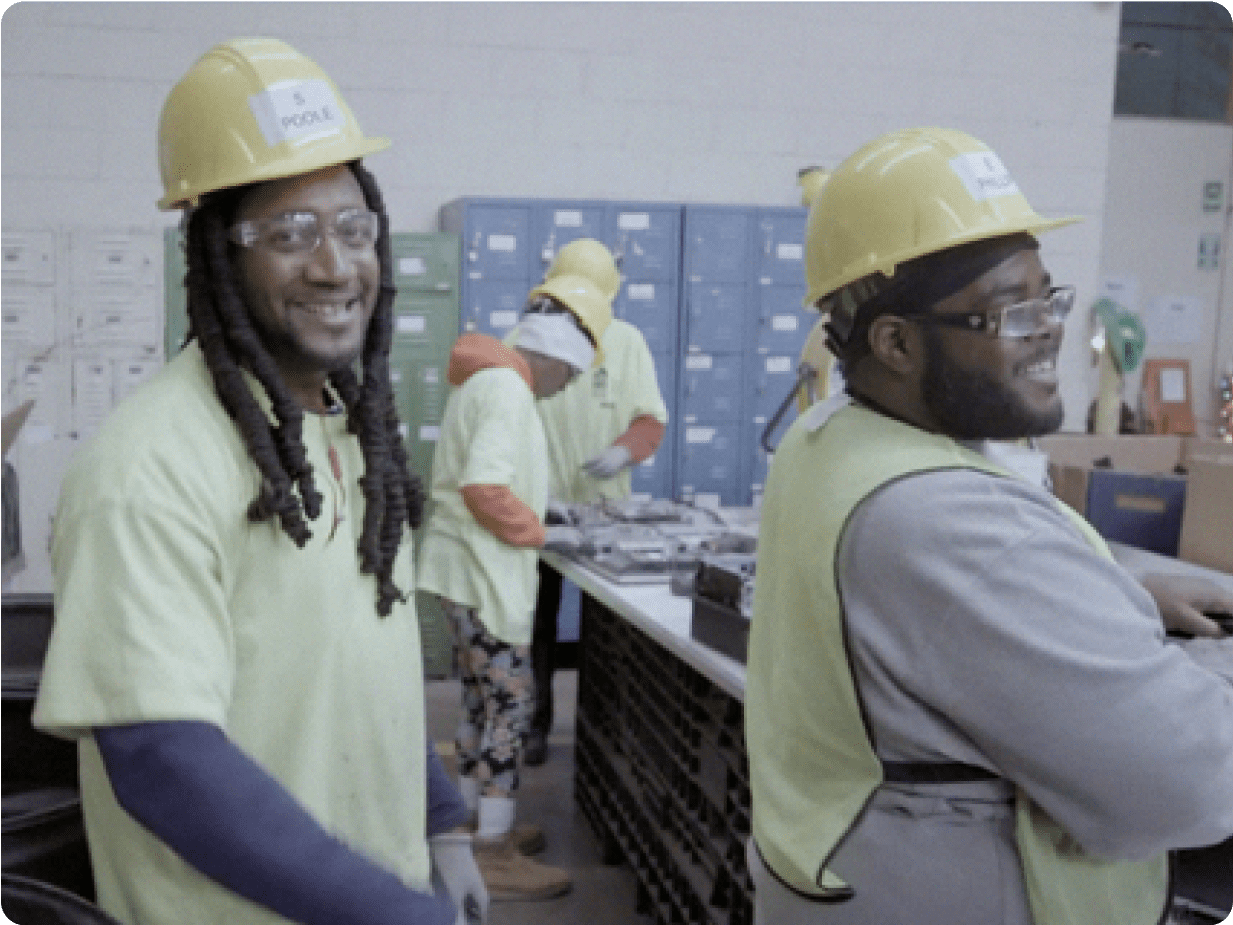 Two men with hard hats on smiling at the camera.