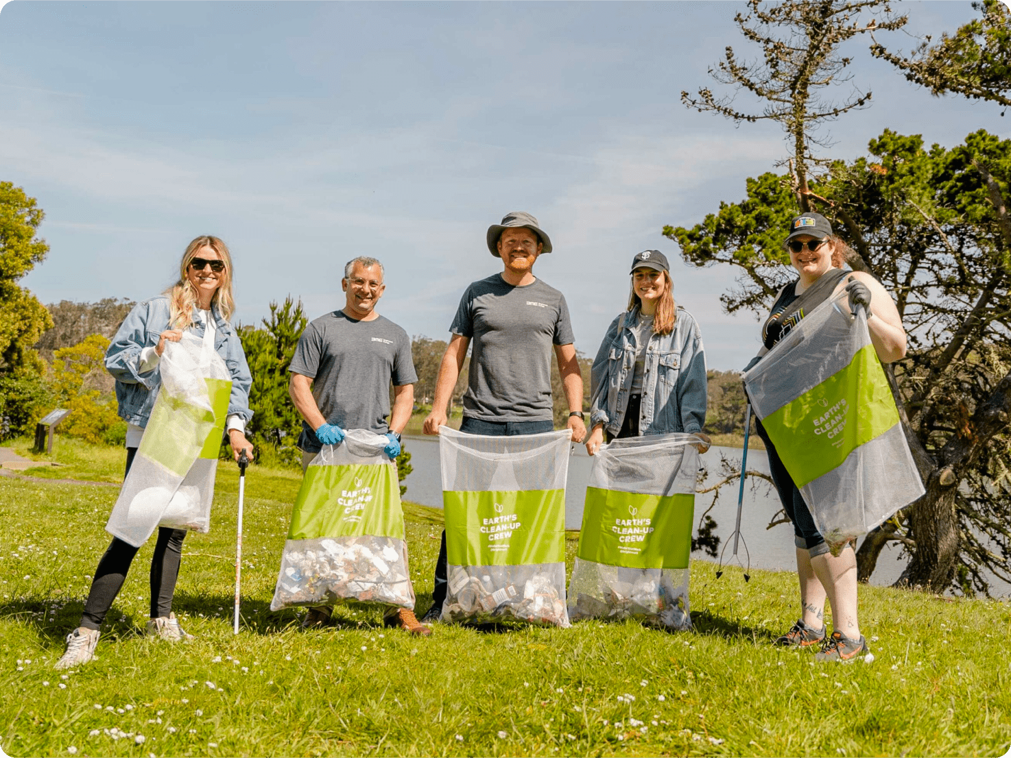 Five people on the Brightmark team at park cleanup event holding trash bags.