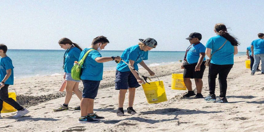 Group of people with buckets cleaning up a beach.